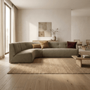 A modern curved sectional sofa upholstered in textured taupe fabric, styled with three throw pillows in a minimalist, warm-toned living room.
