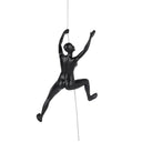 A matte black sculpture of a woman climbing, mounted on a vertical steel wire.