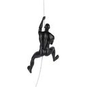 A matte black sculpture of a climbing man in mid-action, suspended with a wire against a white background.
